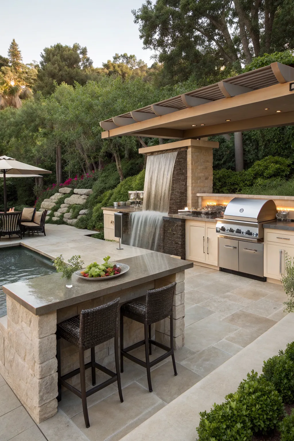 Luxury outdoor kitchen beside pool with stone waterfall island, grill, bar stools, and pergola